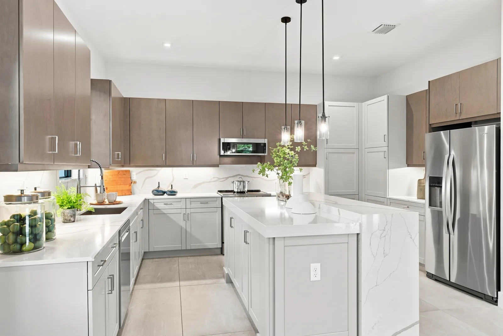 Kitchen with wood upper cabinets, white quartz counters and pendant lights