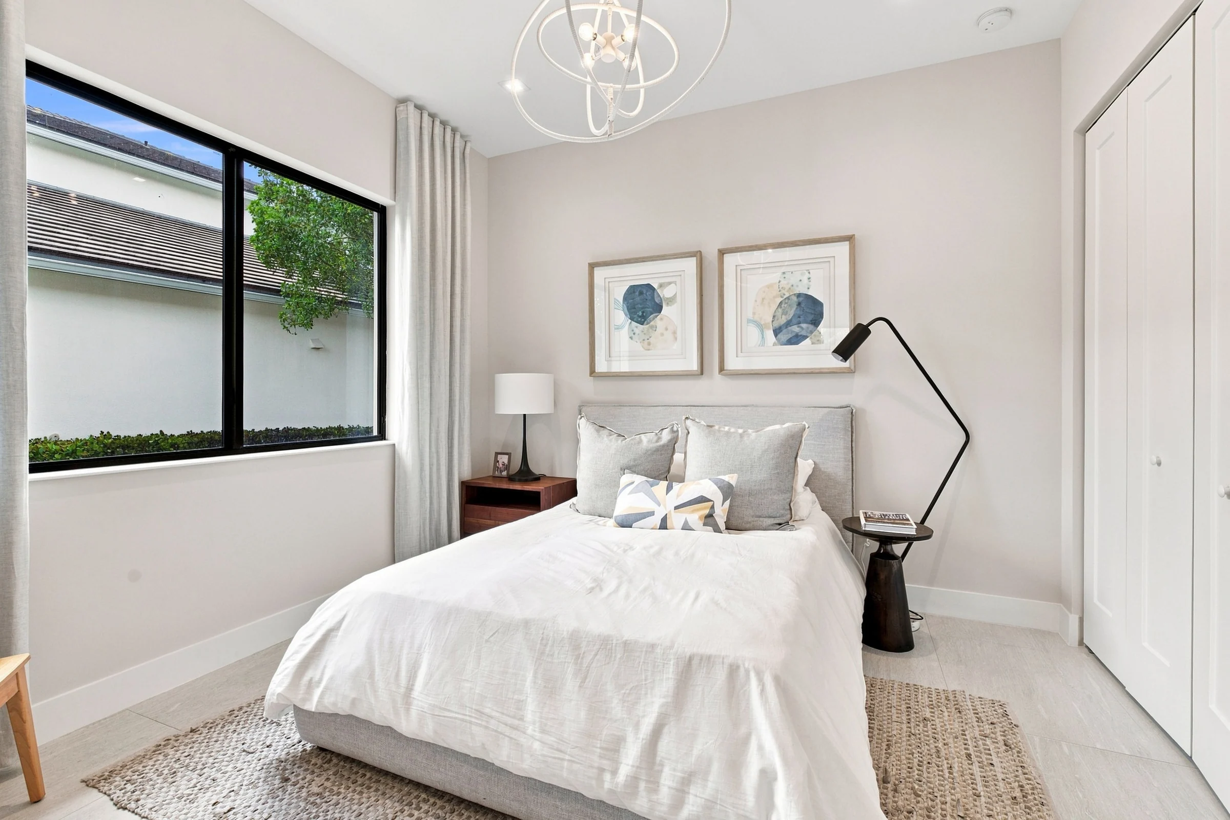 Guest bedroom with framed botanical prints and a floor lamp
