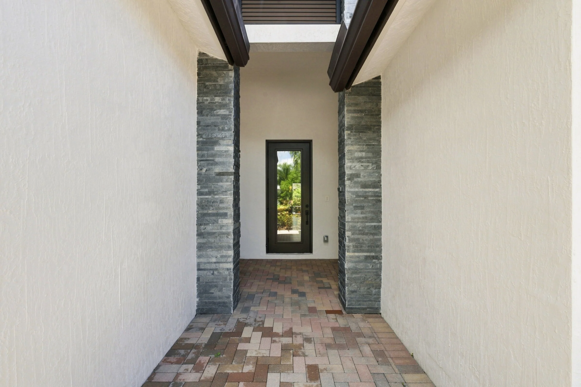 Covered entry walkway with stone columns and a paver floor