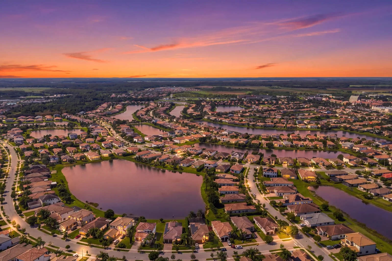 The same aerial view converted to a sunset sky with warm window and street lights