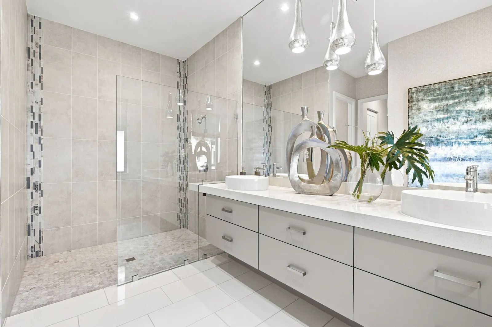 Primary bath with a glass shower, double vanity and glass pendant lights