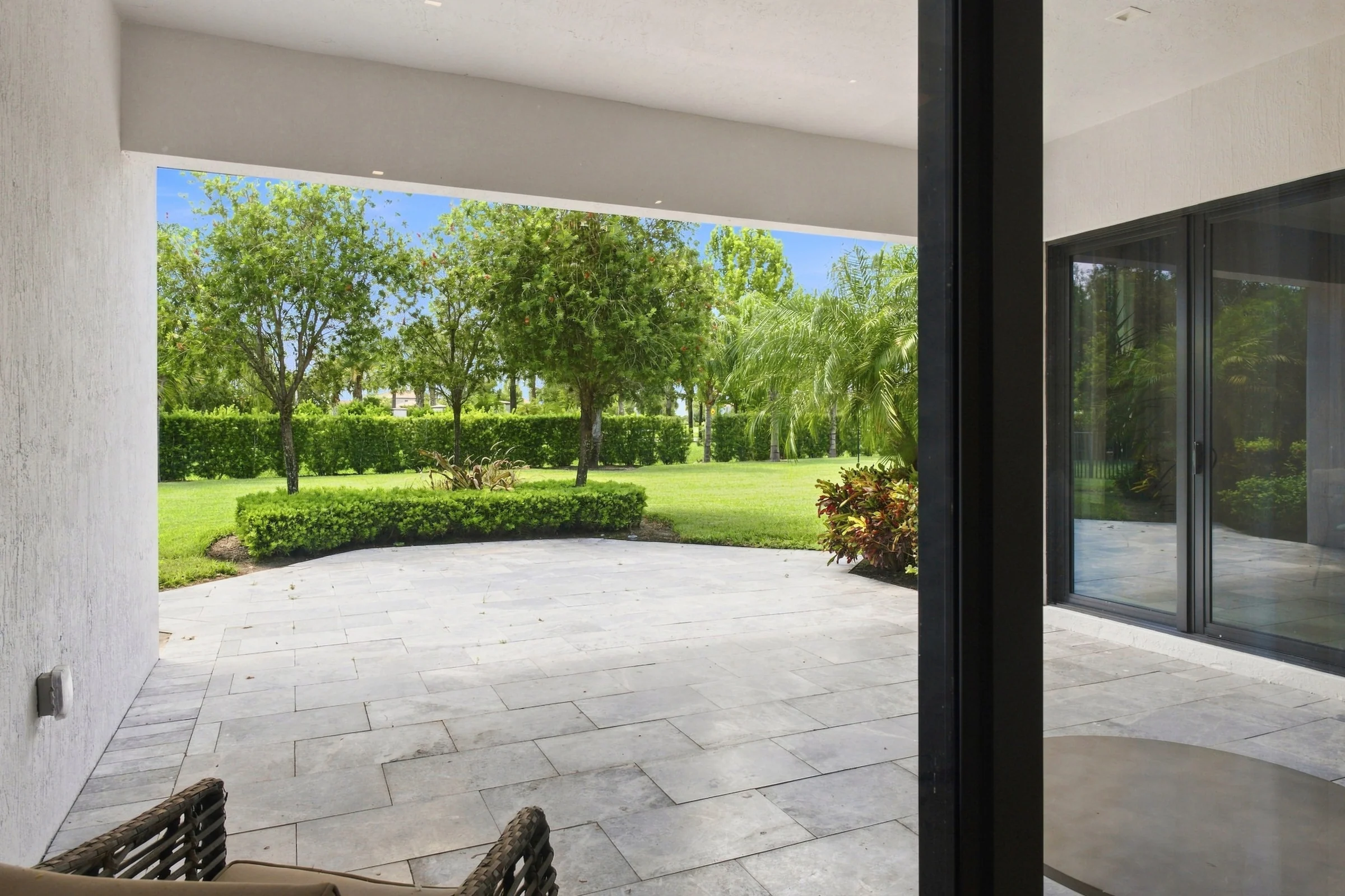 Covered lanai opening to a lawn and hedges
