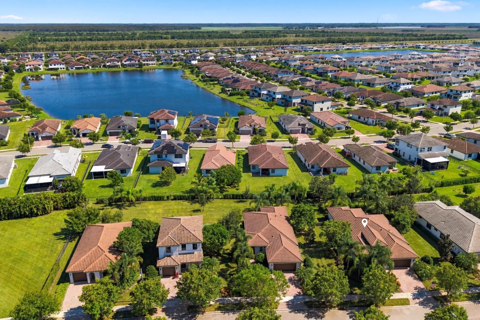 Aerial photograph of a South Florida neighborhood and lake with the featured home marked by a pin