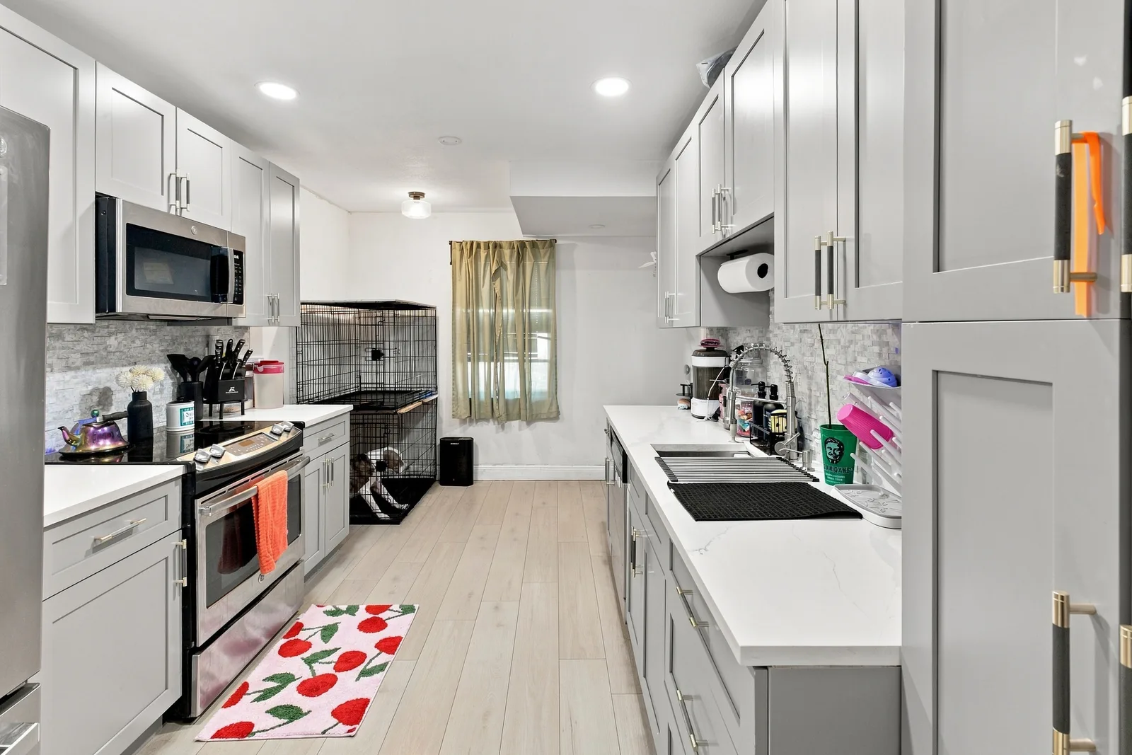 Galley kitchen with personal items on counters, a pet crate and a floor mat
