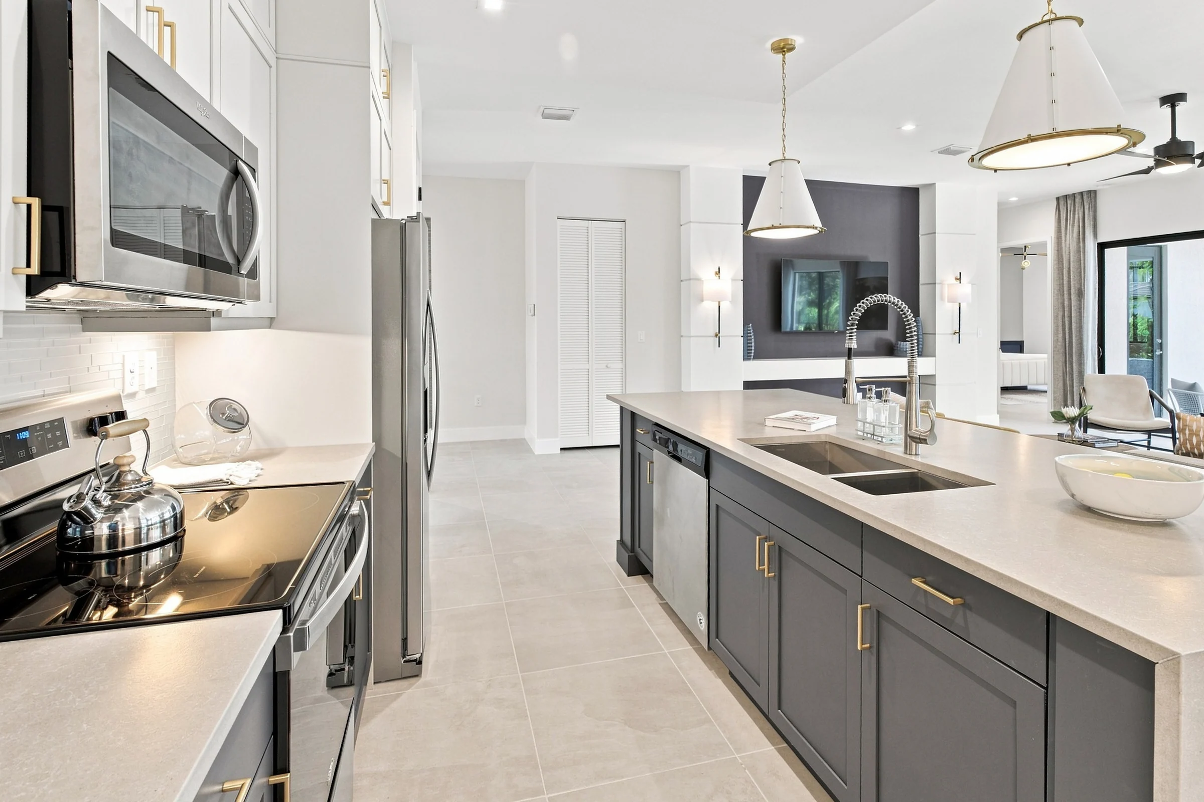 Kitchen counter with a sink and stainless appliances leading toward the living area