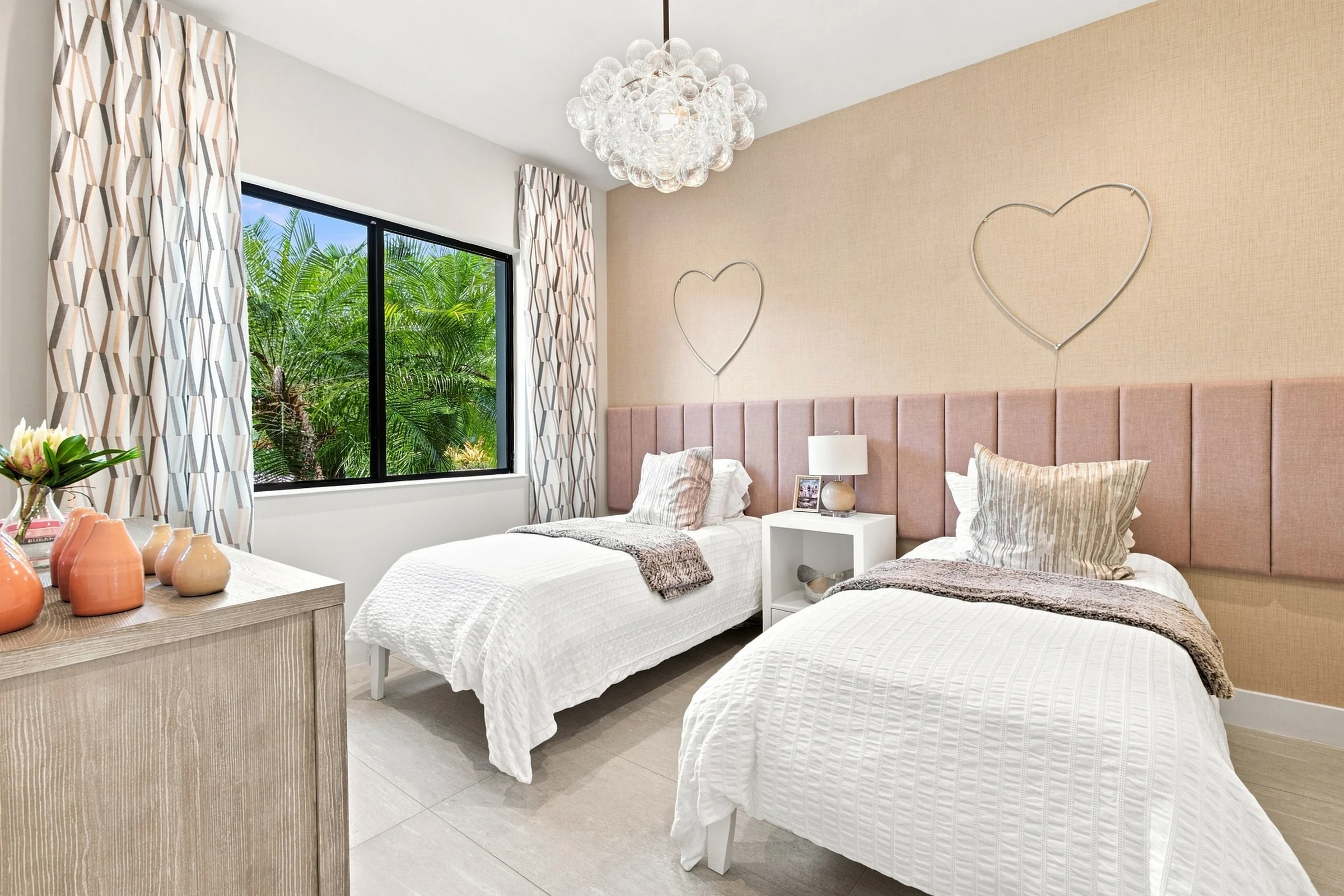 Bedroom with twin beds, a pink upholstered headboard and chandelier