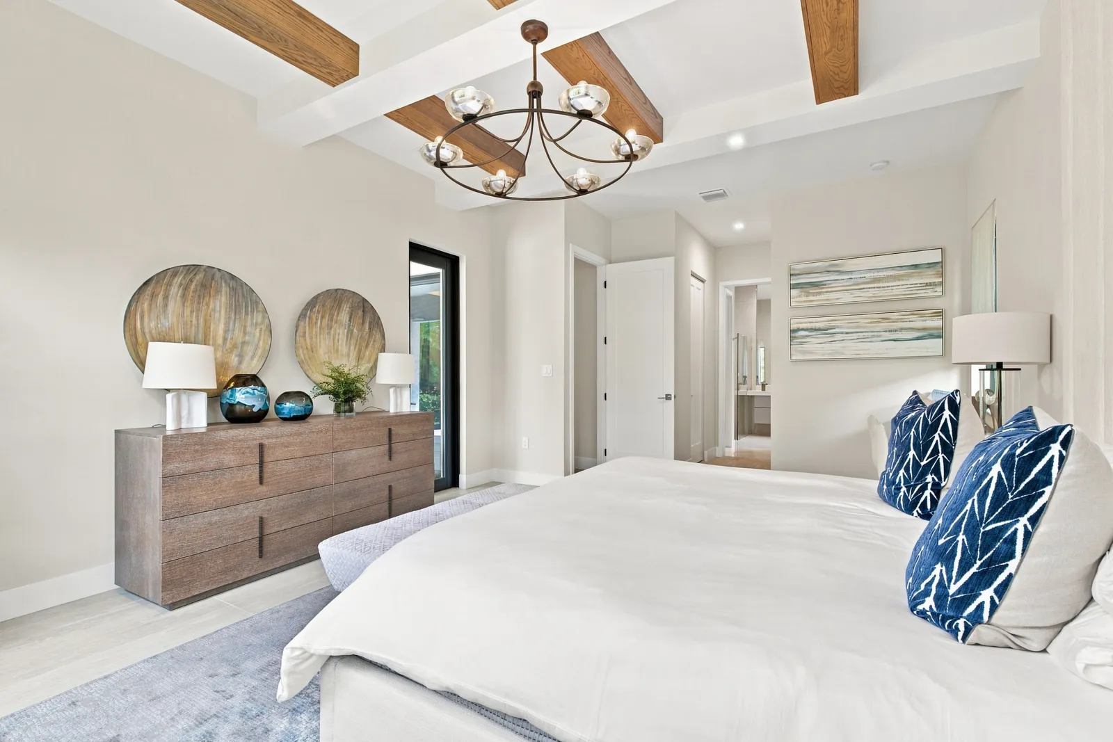 Bedroom with wood ceiling beams, a dresser and blue accent pillows