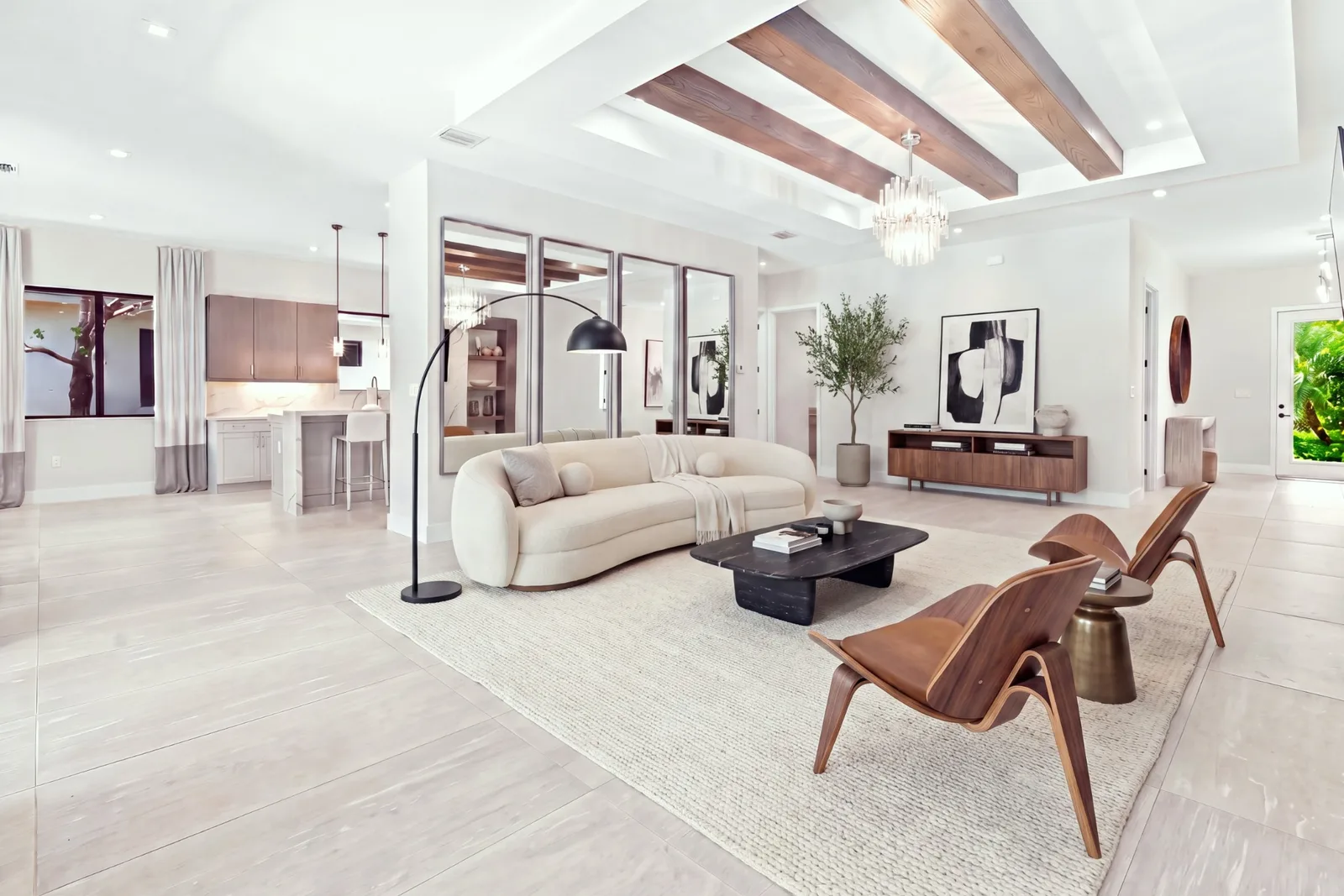 The same living room restyled with a curved sofa, lounge chairs, rug and decor