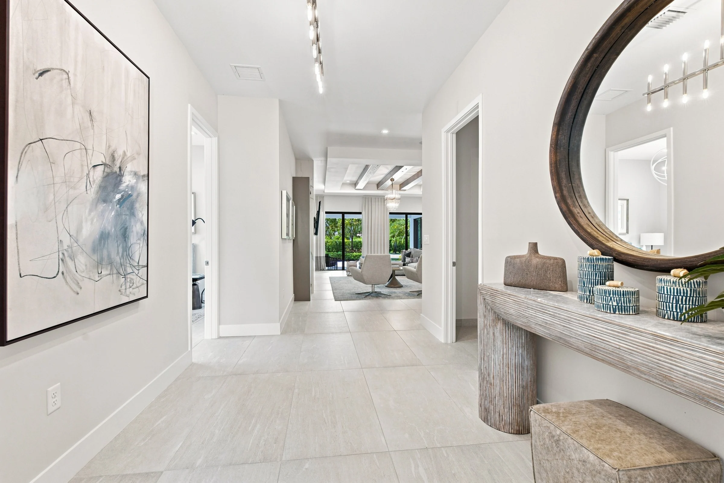 Foyer with abstract artwork, a round mirror and a view through the home