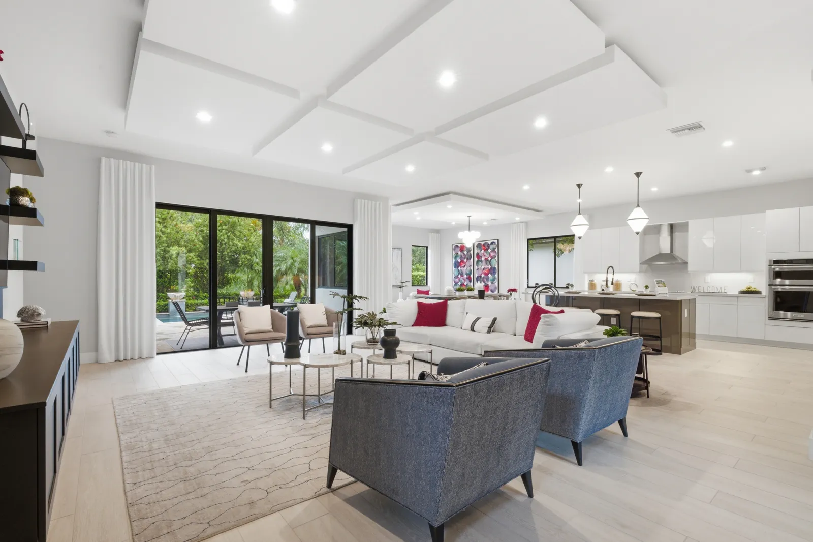 Living room with navy armchairs and coffered ceiling opening to the kitchen