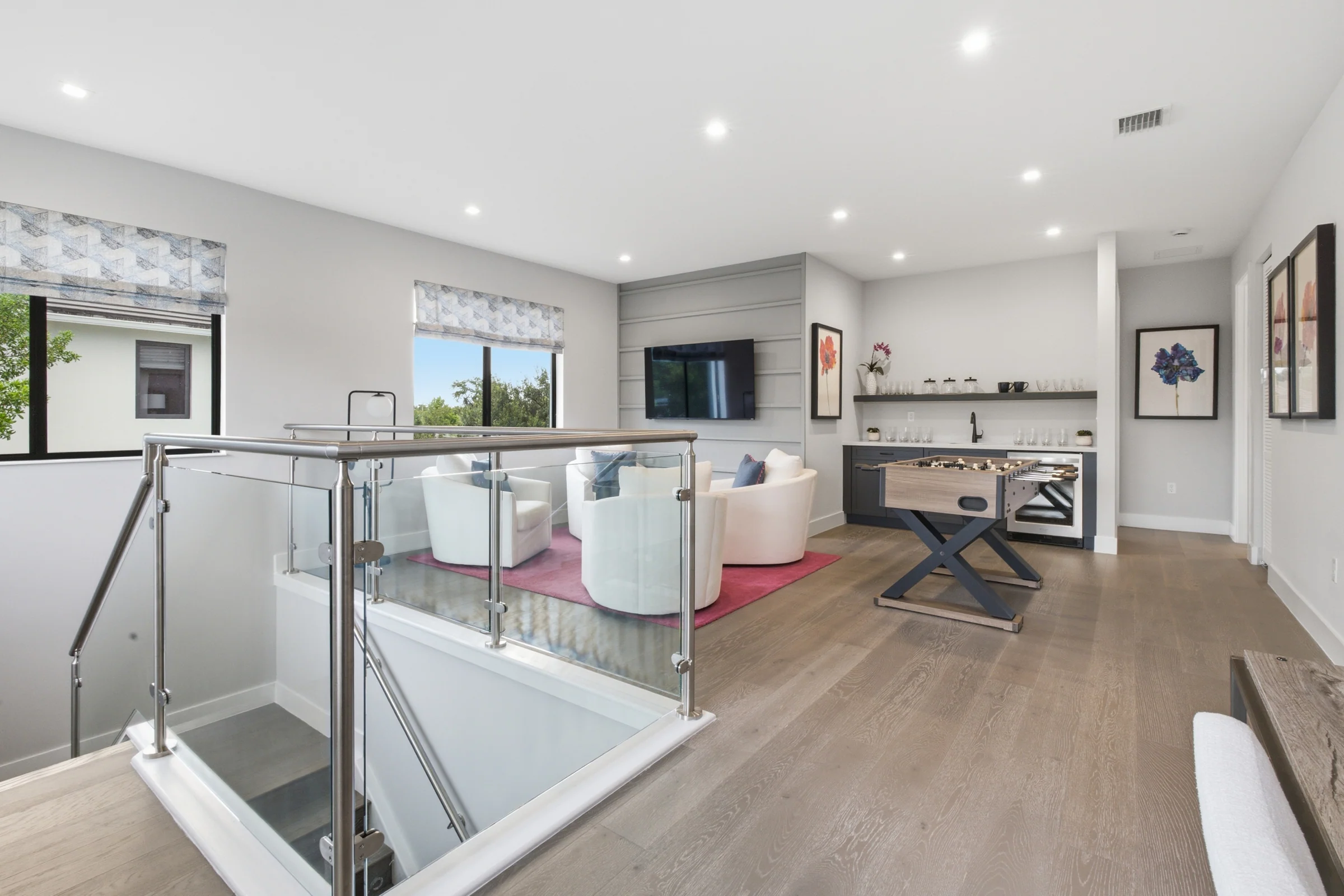 Upstairs loft with a glass stair rail and lounge seating