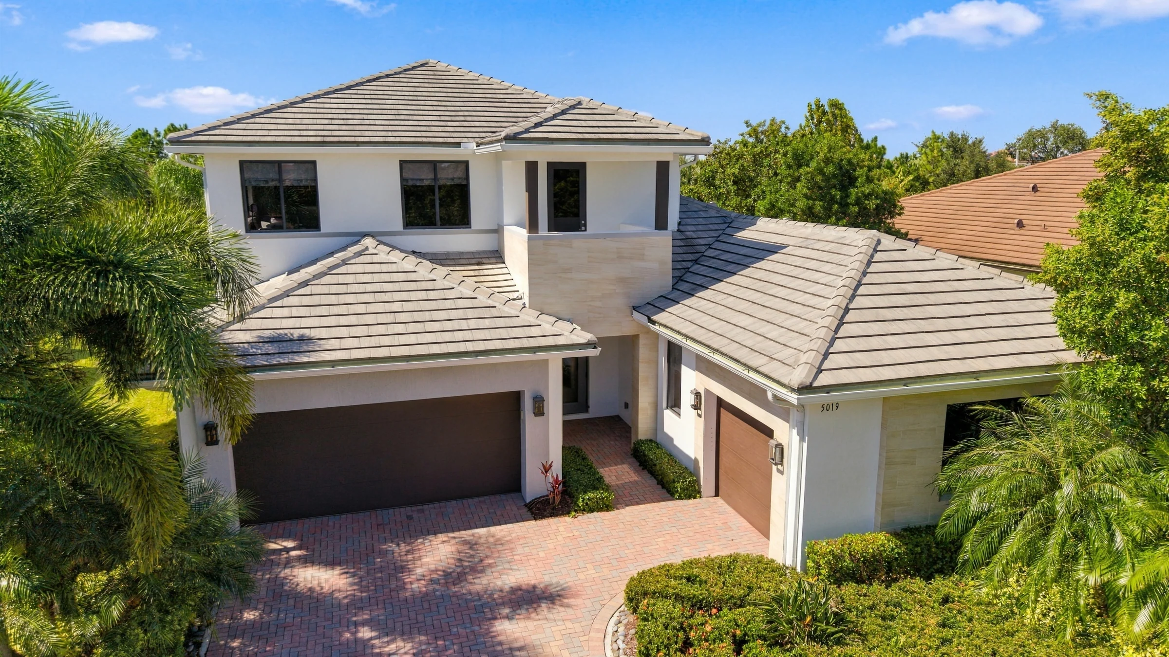 Elevated drone view of the two-story Harbour model home and its paver driveway