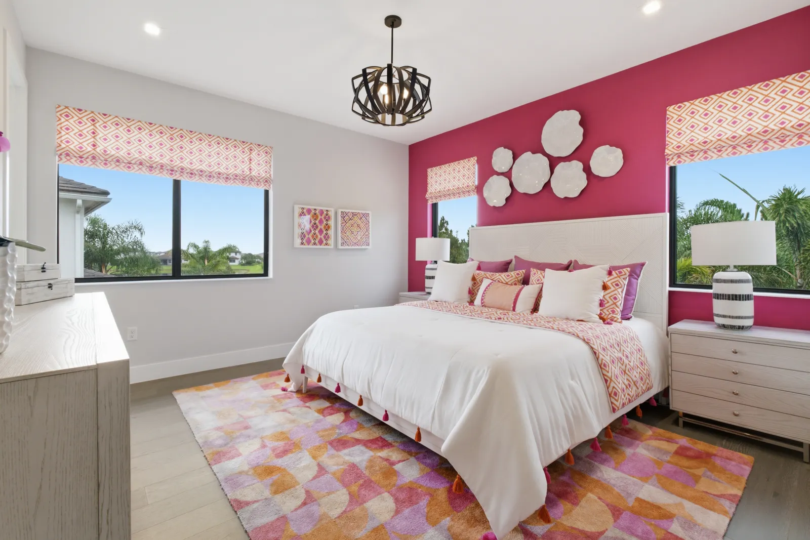 Bright bedroom with a pink accent wall and patterned rug