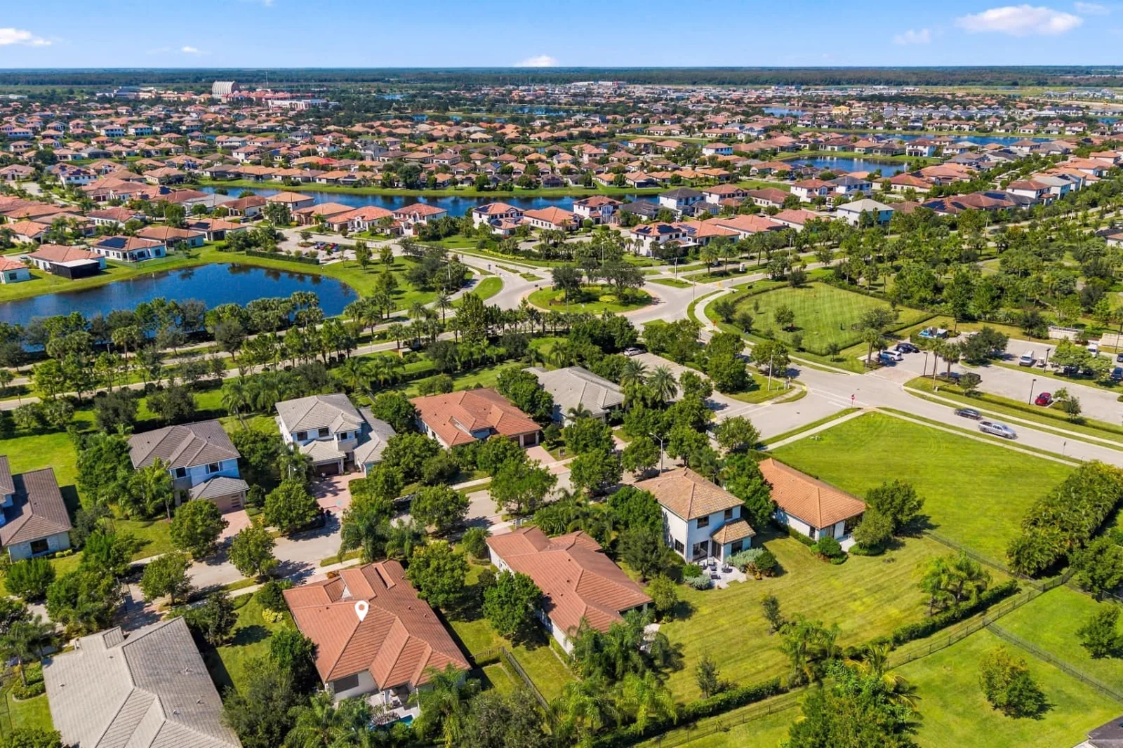 Aerial photograph of a South Florida neighborhood with lakes, a roundabout and the featured home marked with a pin