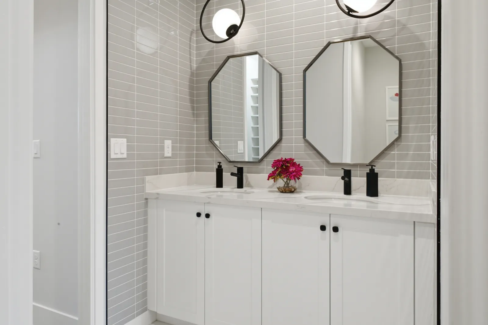 Double vanity with octagonal mirrors and gray tile backsplash