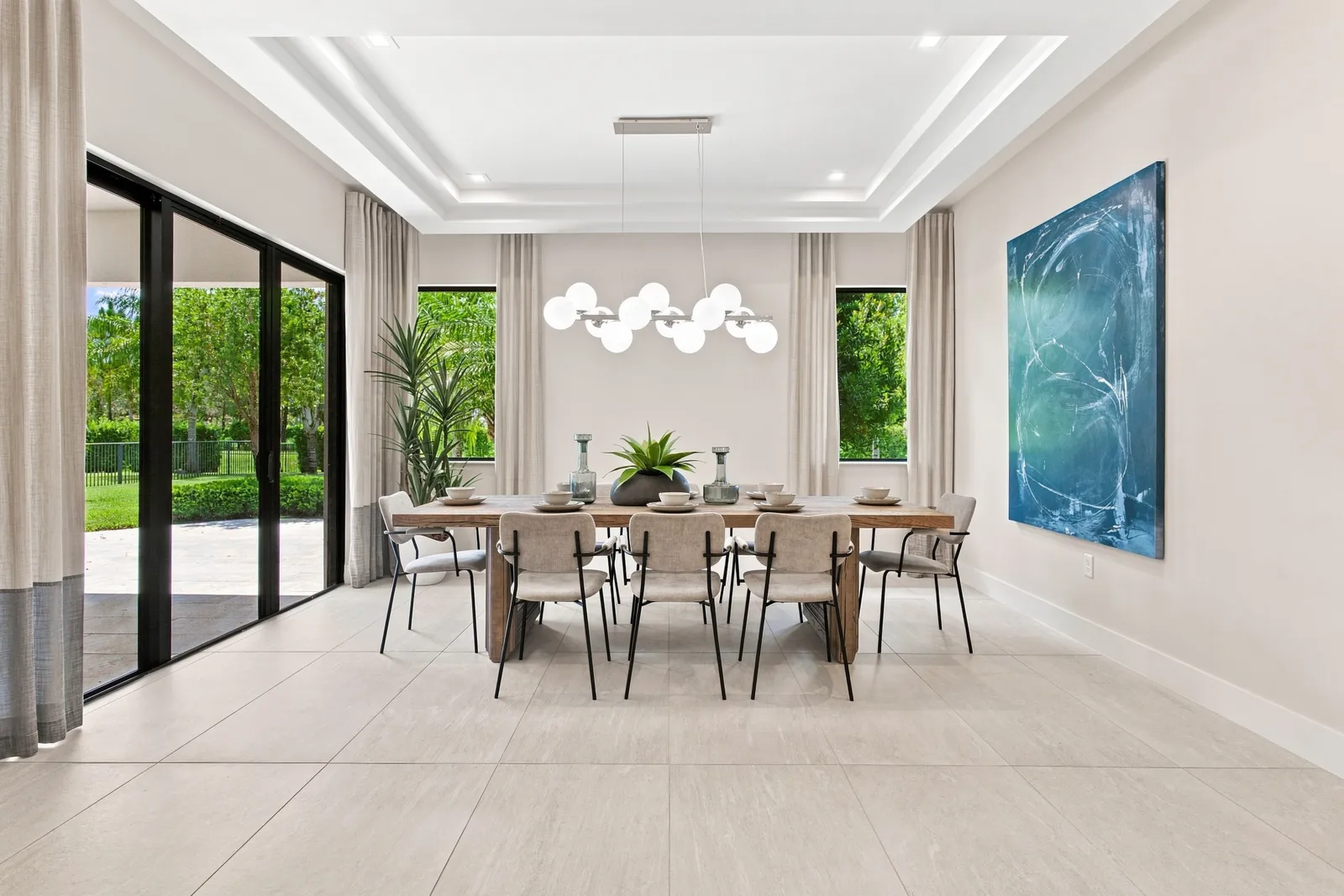 Dining room with a long table, modern chandelier and garden views