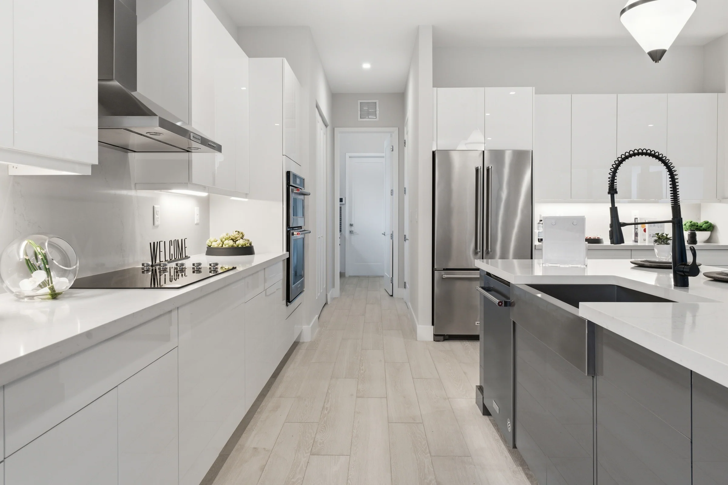 Kitchen galley with glossy white cabinets and a range hood