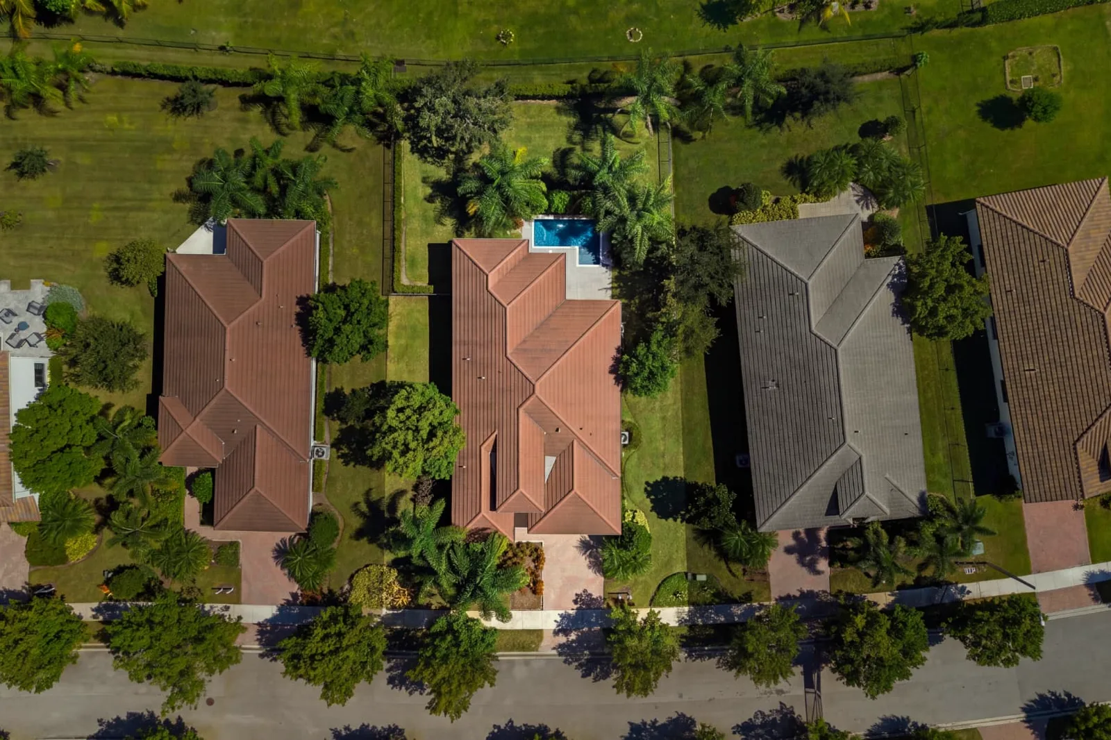 Top-down aerial photograph of a home showing the tile roof, yard and backyard pool between neighboring lots