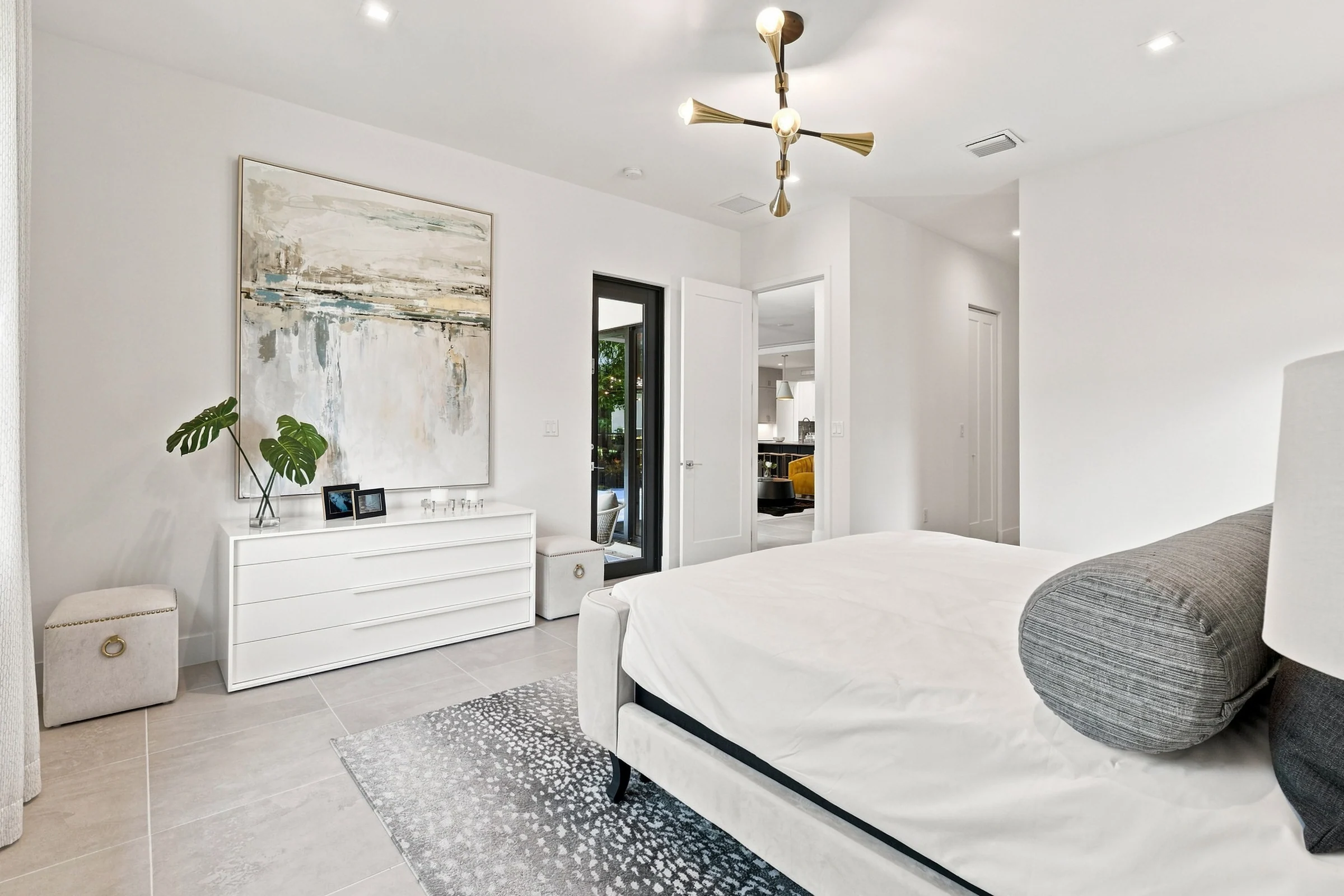 Bedroom with a white dresser, abstract artwork and chandelier